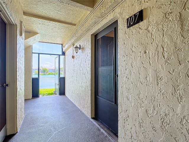 corridor with beamed ceiling and a textured ceiling