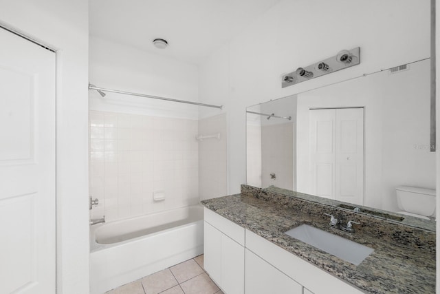 full bathroom with tile floors, large vanity, toilet, and tiled shower / bath combo