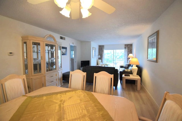 dining area with a textured ceiling, ceiling fan, and hardwood / wood-style floors