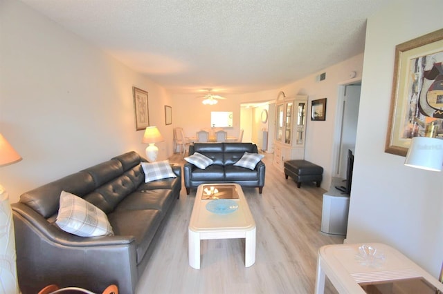 living room featuring ceiling fan, hardwood / wood-style flooring, and a textured ceiling