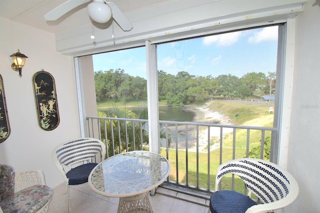 sunroom featuring ceiling fan and a water view