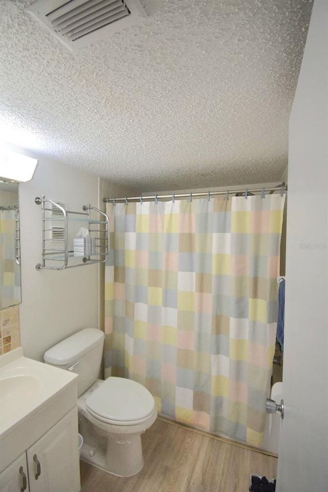 bathroom featuring a textured ceiling, hardwood / wood-style flooring, toilet, and vanity