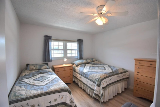 bedroom with a textured ceiling, ceiling fan, and hardwood / wood-style floors