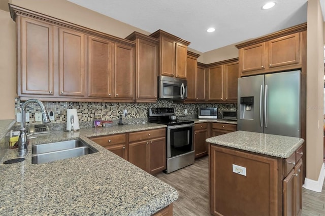 kitchen with a center island, stainless steel appliances, hardwood / wood-style floors, sink, and tasteful backsplash