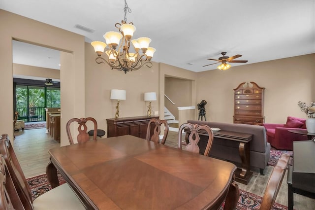 dining area with ceiling fan with notable chandelier and hardwood / wood-style floors