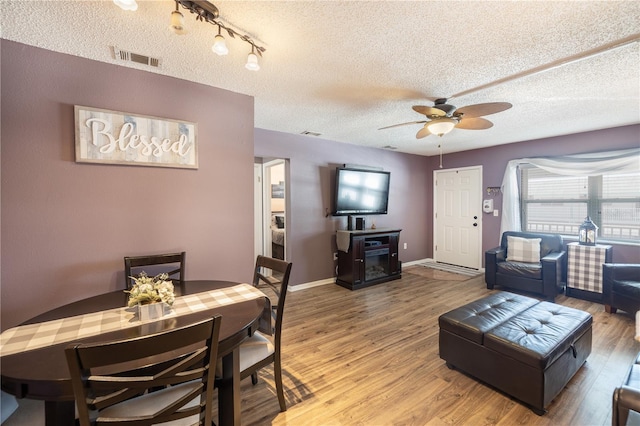 dining room with a textured ceiling, ceiling fan, and hardwood / wood-style floors