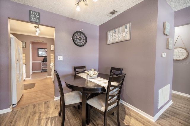 dining space featuring light hardwood / wood-style flooring and a textured ceiling