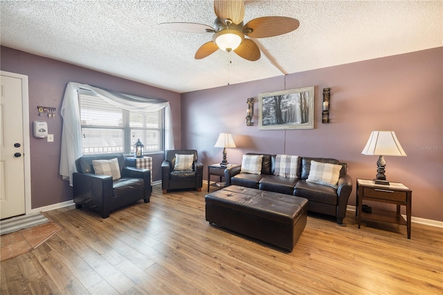 living room featuring light hardwood / wood-style floors, a textured ceiling, and ceiling fan