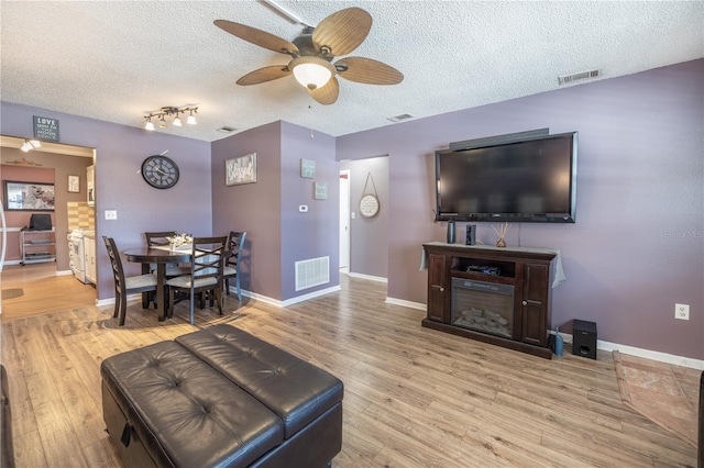 living room with hardwood / wood-style flooring, ceiling fan, a textured ceiling, and rail lighting