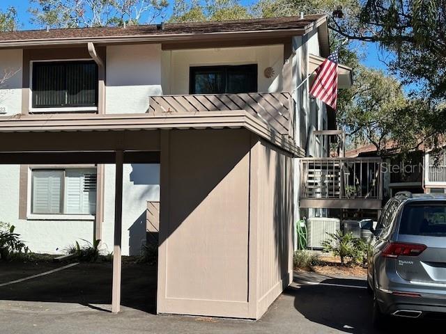 view of side of home with covered parking, central AC, and stucco siding