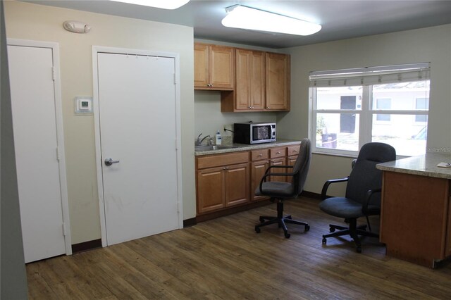 office featuring built in desk, sink, and dark hardwood / wood-style floors