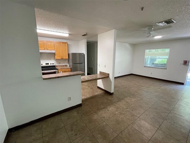 kitchen with dark tile flooring, stainless steel appliances, and a textured ceiling