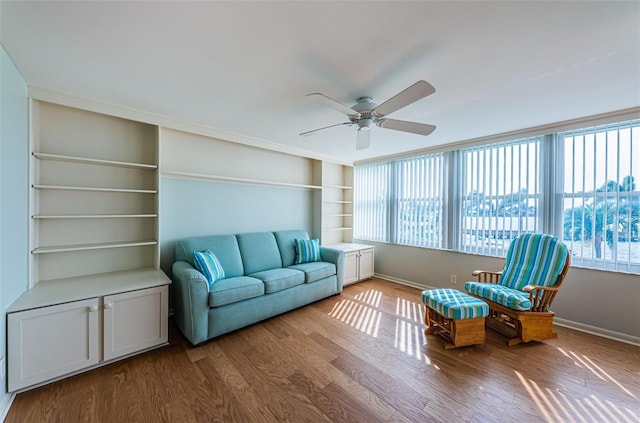 living room featuring built in shelves, light wood-type flooring, and ceiling fan