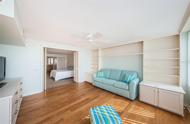 living room with ceiling fan, light hardwood / wood-style floors, and built in shelves