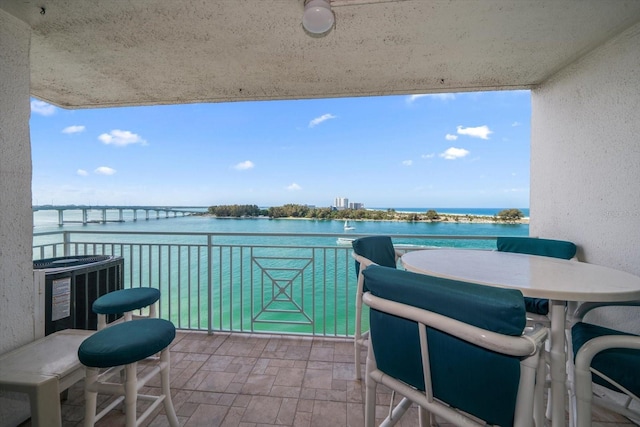 balcony featuring central AC unit and a water view