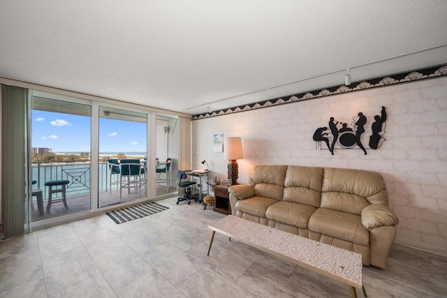 tiled living room with a water view, a textured ceiling, and rail lighting