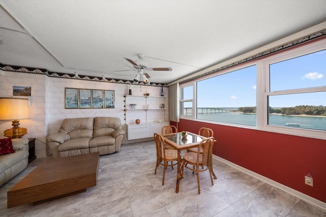 tiled living room featuring a textured ceiling, ceiling fan, and a water view