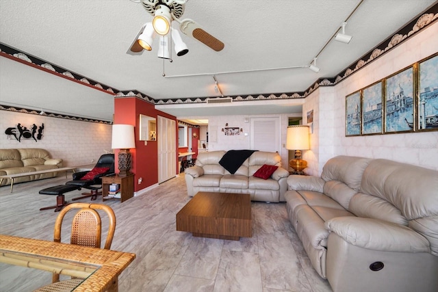 living room with track lighting, ceiling fan, and a textured ceiling