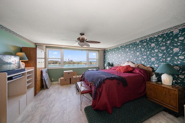 tiled bedroom featuring ceiling fan, a textured ceiling, and a water view