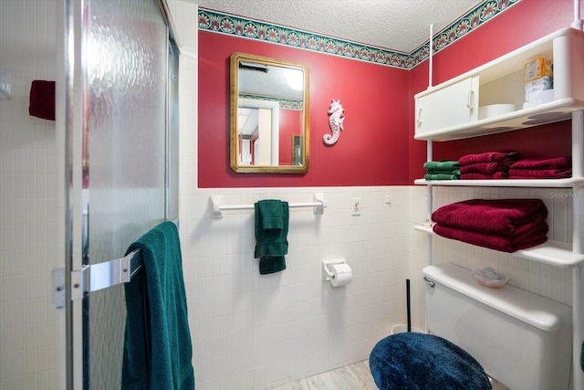 bathroom with tile walls, a textured ceiling, and toilet