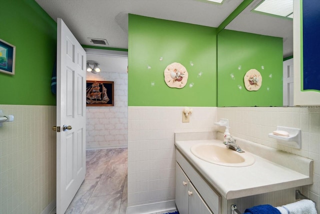 bathroom with tile flooring, tile walls, a textured ceiling, and large vanity