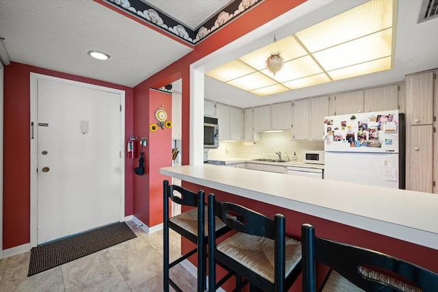 kitchen featuring sink, a textured ceiling, white appliances, and light tile floors