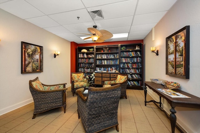 living area with tile floors, ceiling fan, and a paneled ceiling