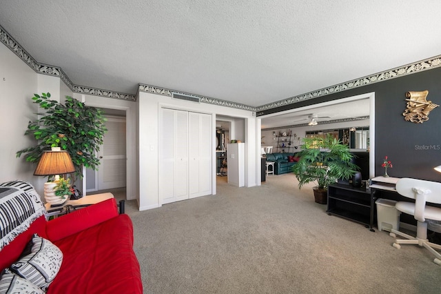 living room featuring carpet flooring, ceiling fan, and a textured ceiling