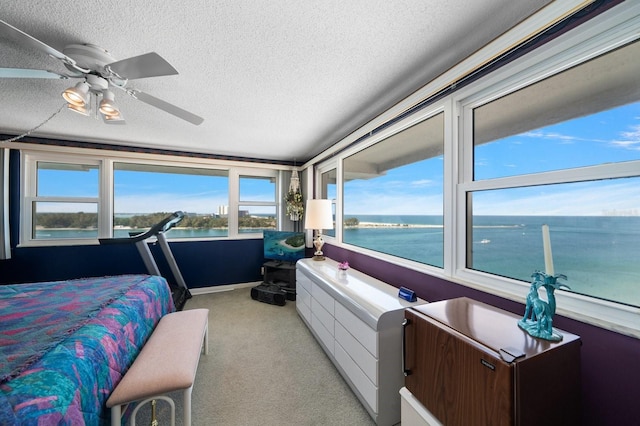 carpeted bedroom featuring ceiling fan, a textured ceiling, and a water view