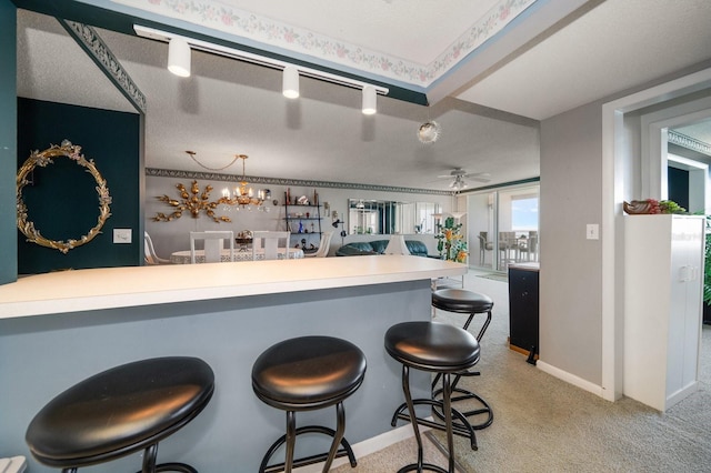 kitchen featuring a textured ceiling, light carpet, a breakfast bar, track lighting, and ceiling fan