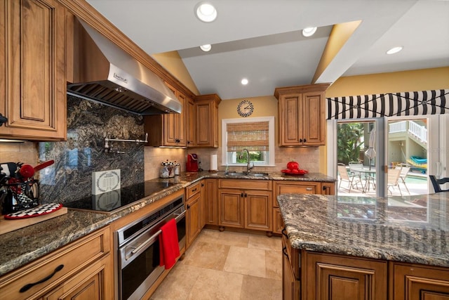 kitchen featuring wall chimney range hood, sink, stainless steel oven, and tasteful backsplash