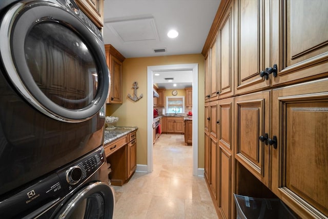 washroom featuring sink, stacked washer and clothes dryer, light tile flooring, and cabinets