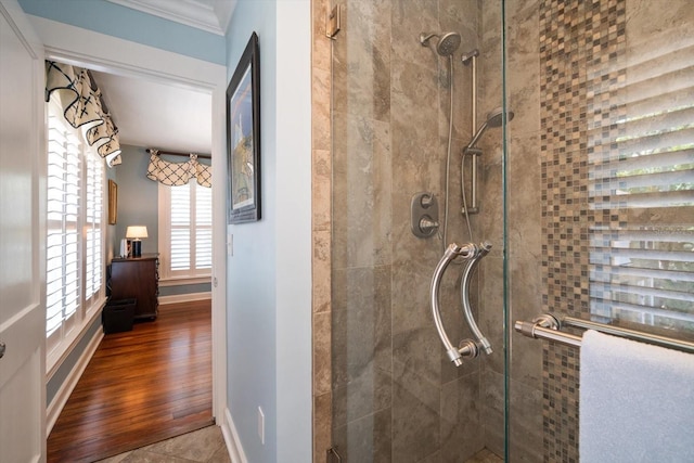 bathroom with a shower with shower door, hardwood / wood-style flooring, and ornamental molding