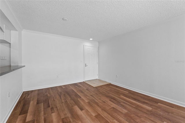 spare room with a textured ceiling, hardwood / wood-style flooring, and crown molding