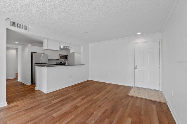 unfurnished living room featuring ornamental molding, a textured ceiling, and light hardwood / wood-style flooring