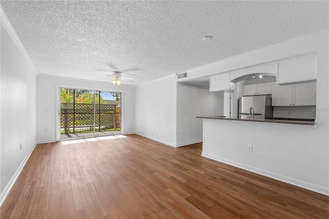 unfurnished living room with ceiling fan, crown molding, hardwood / wood-style floors, and a textured ceiling