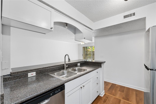 kitchen with sink, dark hardwood / wood-style flooring, a textured ceiling, white cabinets, and appliances with stainless steel finishes