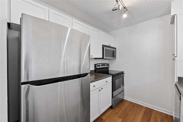 kitchen with dark hardwood / wood-style flooring, white cabinetry, a textured ceiling, and appliances with stainless steel finishes