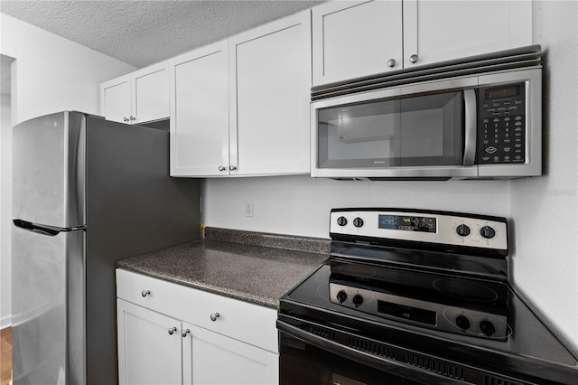 kitchen featuring a textured ceiling, white cabinetry, and stainless steel appliances