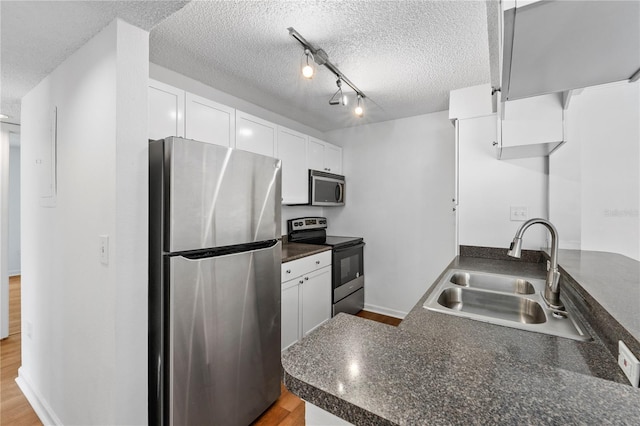 kitchen with kitchen peninsula, white cabinetry, sink, and stainless steel appliances