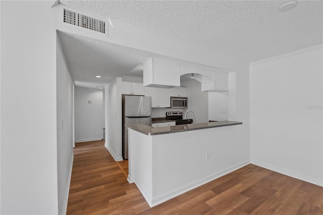 kitchen featuring white cabinets, a textured ceiling, kitchen peninsula, and stainless steel appliances