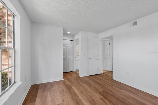 unfurnished bedroom featuring light hardwood / wood-style floors, a textured ceiling, and a closet