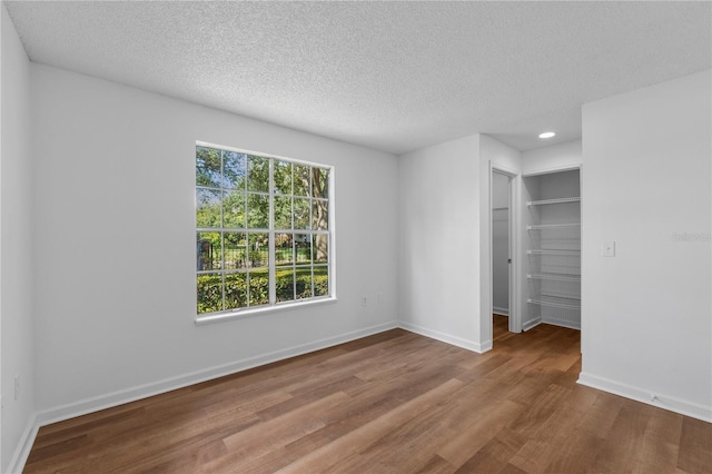 unfurnished room with a textured ceiling, light hardwood / wood-style floors, and a healthy amount of sunlight