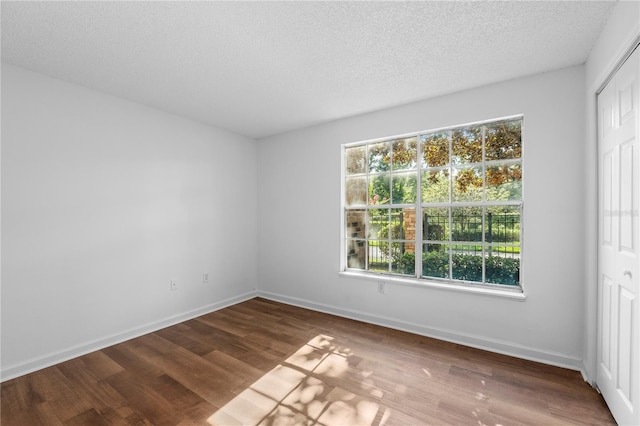 empty room with a healthy amount of sunlight, a textured ceiling, and wood-type flooring