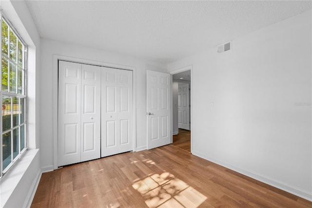 unfurnished bedroom with a closet, hardwood / wood-style floors, and a textured ceiling