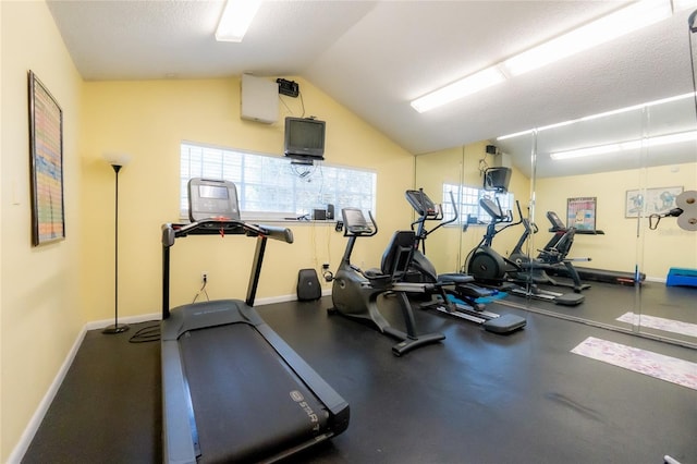 gym with lofted ceiling, baseboards, and a textured ceiling