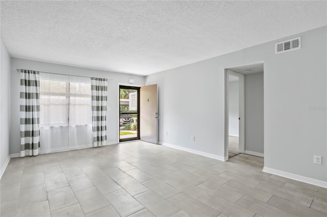 tiled empty room featuring a textured ceiling