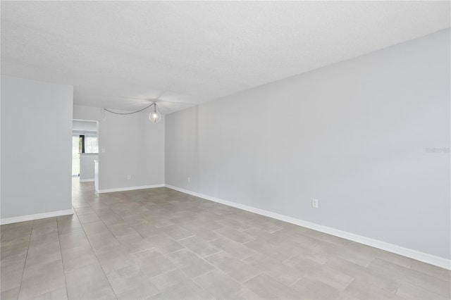 empty room with a textured ceiling and light tile flooring