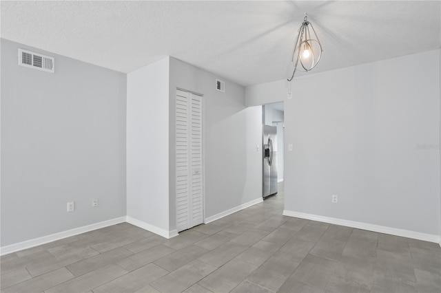 tiled empty room featuring a textured ceiling