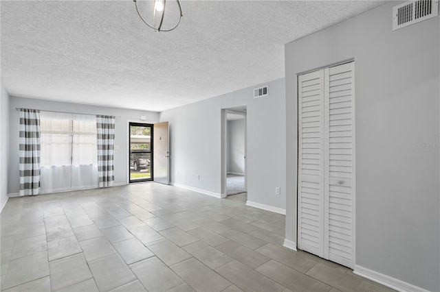 spare room with light tile flooring and a textured ceiling